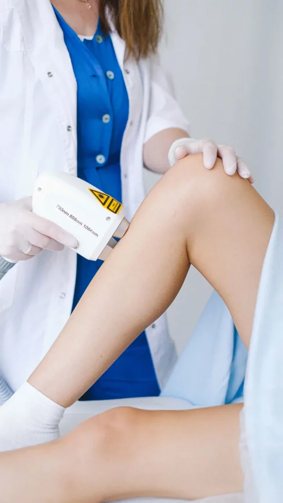 Profesional sanitaria aplicando tratamiento láser en una pierna para ilustrar las arañas vasculares